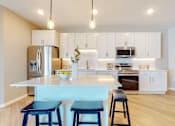 Thumbnail 3 of 102 - A kitchen with a white counter and blue stools.