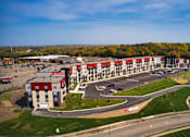 Thumbnail 15 of 102 - A large building with a parking lot in front of it.