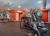 Thumbnail 34 of 102 - A gym with orange walls and a variety of exercise equipment.