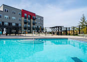 Thumbnail 40 of 102 - A swimming pool in front of a multi-story apartment building.