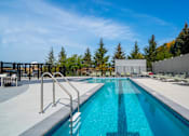 Thumbnail 41 of 102 - A large outdoor swimming pool surrounded by lounge chairs and trees.