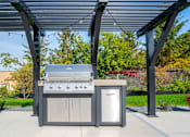 Thumbnail 44 of 102 - A modern outdoor kitchen setup with a grill, sink, and cabinet.