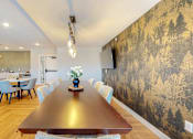 Thumbnail 49 of 102 - A long wooden table is surrounded by chairs in a room with a forest wallpaper.