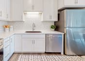 Thumbnail 63 of 102 - A kitchen with white cabinets and a stainless steel refrigerator.