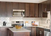 Thumbnail 11 of 98 - A kitchen with dark brown cabinets and a stainless steel refrigerator.