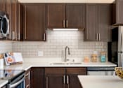 Thumbnail 12 of 98 - A kitchen with brown cabinets and a white countertop.