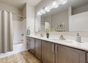 Thumbnail 32 of 98 - A bathroom with a shower curtain, two sinks, and a large mirror.