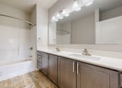 Thumbnail 42 of 98 - A bathroom with a white tub, sink, and mirror.