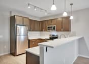 Thumbnail 45 of 98 - A kitchen with a white counter and wooden cabinets.