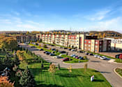Thumbnail 54 of 98 - A large apartment complex with a parking lot in front.