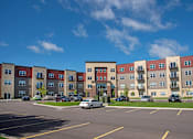 Thumbnail 56 of 98 - A parking lot in front of a multi-story apartment building.