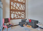 Thumbnail 58 of 98 - A living room with a grey couch, a red chair and a wooden wall panel.