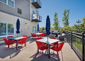 Thumbnail 88 of 98 - A patio with red chairs and tables is surrounded by a black fence.