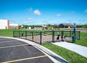 Thumbnail 90 of 98 - A parking lot with a black fence and a green trash can.