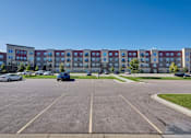 Thumbnail 92 of 98 - A parking lot with a building in the background.
