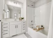 Thumbnail 12 of 16 - A white bathroom with a large mirror and a bathtub.