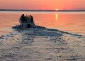 Thumbnail 20 of 24 - a boat in the water on Lake Murray with a sunset in the background at The Residence at Marina Bay, Irmo, South Carolina
