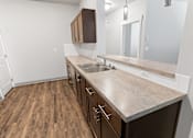 Thumbnail 6 of 53 - A kitchen with brown cabinets and a wooden floor.at The Brix Apartments, Spokane Valley, WA, 99037