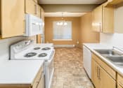 Thumbnail 31 of 73 - A kitchen with a white stove top oven and a white microwave above it at Graymayre Crossing Apartments, Spokane, WA, 99208