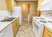 Thumbnail 32 of 73 - A kitchen with white appliances and wooden cabinets at Graymayre Crossing Apartments, WA, 99208