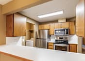 Thumbnail 44 of 73 - A kitchen with wooden cabinets and stainless steel appliances at Graymayre Crossing Apartments, Spokane, WA, 99208