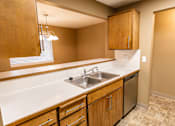 Thumbnail 46 of 73 - A kitchen with wooden cabinets and a white countertop at Graymayre Crossing Apartments, Spokane, WA, 99208
