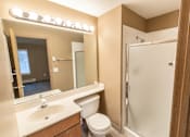Thumbnail 56 of 73 - A bathroom with a toilet, sink, mirror, and shower at Graymayre Crossing Apartments, Spokane, 99208