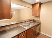 Thumbnail 59 of 73 - A kitchen with a sink and brown cabinets at Graymayre Crossing Apartments, Spokane, WA, 99208