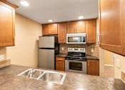 Thumbnail 60 of 73 - A kitchen with a stove, oven, refrigerator, and microwave at Graymayre Crossing Apartments, Spokane, WA, 99208