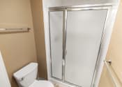 Thumbnail 73 of 73 - A white toilet sits next to a walk-in shower with a glass doorat Graymayre Crossing Apartments, Spokane