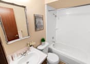 Thumbnail 10 of 12 - A white toilet sits next to a white sink in a bathroom.