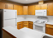 Thumbnail 15 of 73 - A kitchen with wooden cabinets and white appliances at Graymayre Crossing Apartments, Spokane, 99208