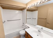 Thumbnail 25 of 73 - A white toilet is in a small bathroom with a white tub and sink at Graymayre Crossing Apartments, Spokane, WA, 99208