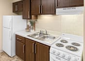 Thumbnail 7 of 12 - A kitchen with a white fridge, white stove, and brown cabinets.