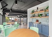 Thumbnail 18 of 63 - a community space with blue tables and chairs and a kitchen