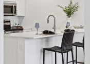 Thumbnail 3 of 63 - a kitchen with white cabinets and a white island with two black stools