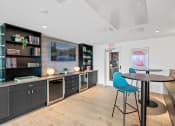 Thumbnail 28 of 63 - Community room with a table and chairs and a kitchen with black cabinets