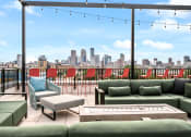 Thumbnail 31 of 63 - Rooftop deck with green couches and chairs and a view of the city