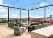 Thumbnail 32 of 63 - a rooftop patio with green couches and chairs and a view of the city