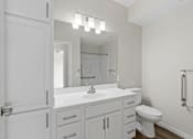 Thumbnail 38 of 39 - A white bathroom with a toilet, sink, and mirror.