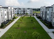Thumbnail 4 of 6 - A view of a grassy area in front of apartment buildings.