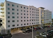Thumbnail 10 of 13 - A large white building with a parking lot in front.