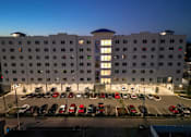 Thumbnail 3 of 13 - A hotel parking lot is full of cars.