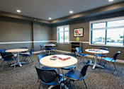 Thumbnail 6 of 13 - A room with tables and chairs and a window.
