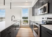 Thumbnail 52 of 63 - a kitchen with black cabinets and stainless steel appliances and a window