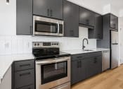 Thumbnail 54 of 63 - a black and white kitchen with stainless steel appliances and black cabinets