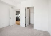 Thumbnail 41 of 63 - an empty living room with white walls and doors to a kitchen