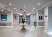 Thumbnail 8 of 11 - A large, well-lit lobby with a round table in the center.