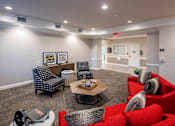 Thumbnail 1 of 11 - A living room with a red couch and a grey chair.