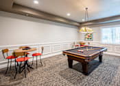 Thumbnail 4 of 11 - A pool table is in the middle of a room with chairs and a table.
